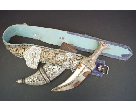 A Middle Eastern Jambiya Knife / Dagger Housed Within A Leather Sheath With White Metal Handle, Complete With Belt. 