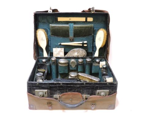 A Drew & Son crocodile skin dressing case, with canvas slip, fitted with silver mounted bottles, monogrammed 'M' with ivory b