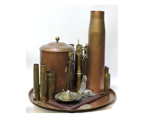 A collection of shell cases, a copper urn, a large tray, and a set of balance scales