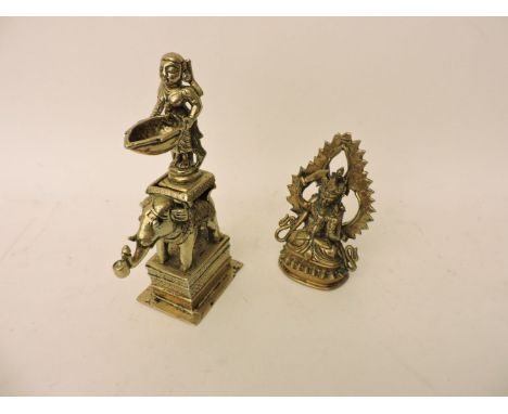 An Indian brass oil lamp, in the form of a figure standing on an elephants back, 21.5cm high, and a brass Indian deity, 14cm 