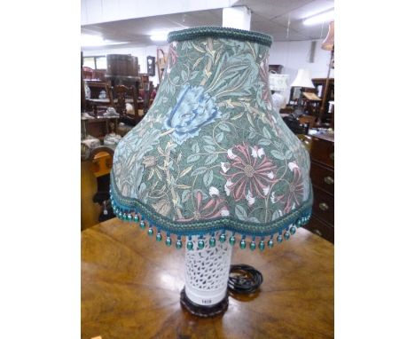 A WHITE PIERCED CERAMIC CYLINDRICAL TABLE LAMP, with hardwood base and William Morris style shade