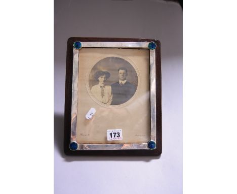 A SILVER MOUNTED PHOTOGRAPH FRAME, on oak easel support, the rectangular silver frame with coloured enamel circular cabochons