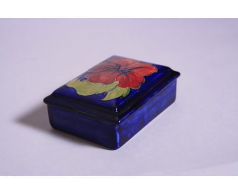 A RECTANGULAR MOORCROFT COVERED TRINKET BOX, Hibiscus pattern on blue ground, impressed marks to base, length approximately 1