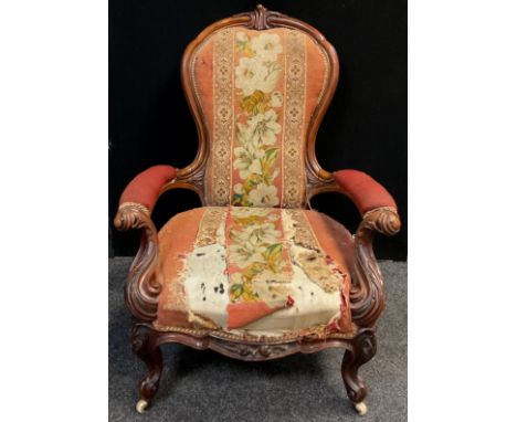 A Victorian carved walnut armchair, stuffed-over back and arms, sprung seat, ornately carved scrolling arms, cabriole legs, c