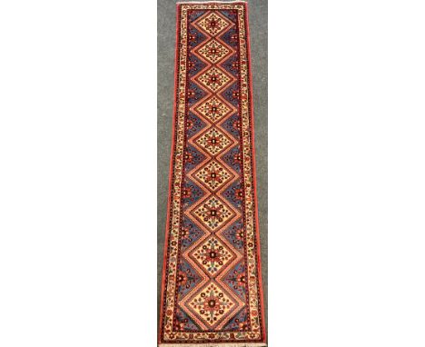 A North-west Persian Rudbar runner carpet, hand-knotted with central row of nine diamond-form medallions, with stylised flora