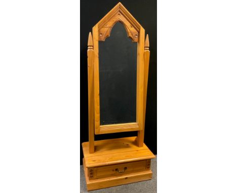 A Gothic style pine Cheval mirror, the mirror having a carved Gothic arch top, single drawer to base, 177cm high x 70cm wide 