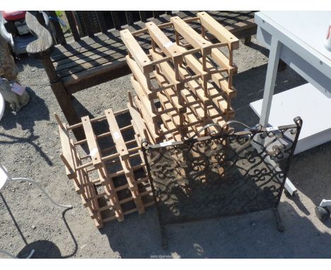 A wrought iron fireguard and two wooden wine bottle racks.