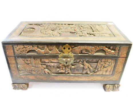 A TABLE TOP CAMPHORWOOD TRUNK  the top and sides having carved decoration depicting figures in various settings, having brass