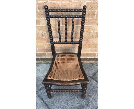 AN EBONISED BOBBIN CHAIR having a cane seat, H 80cm