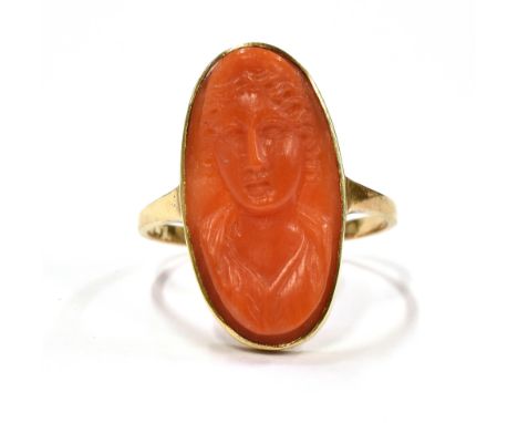 A CAMEO COCKTAIL RING With the coral coloured hardstone cameo measuring approx. 2cm by 1cm on a yellow metal shank and mount 