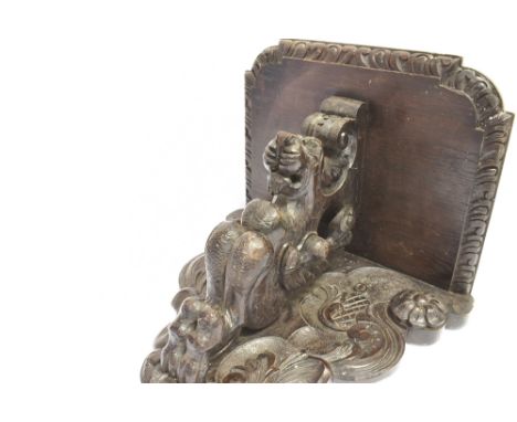 AN EBONISED CLOCK BRACKET  the shelf measuring W 38cm x D 30cm, supported by a seated lion with floral surround, H 35cm x W 3