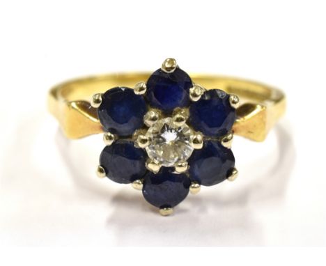 AN 18CT GOLD DIAMOND AND SAPPHIRE SLOWER HEAD RING The central round cut diamond measuring approx. 1cm in diameter, angled sh