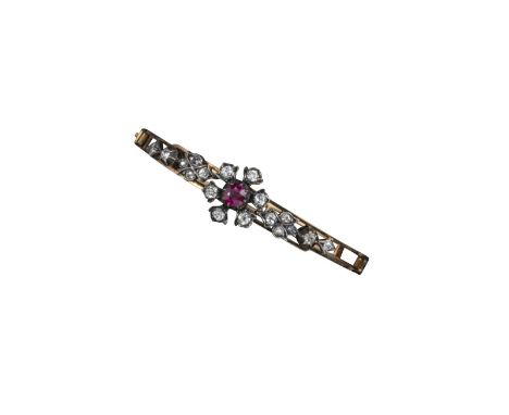 A late Victorian ruby and diamond bangle, the central ruby set within a flowerhead cluster of diamonds within further diamond