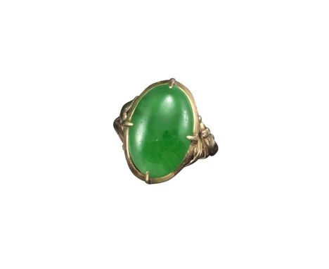 A jade mounted gold ring, the oval-shaped jade cabochon set in gold with two pierced foliate shoulders, size L Accompanied by