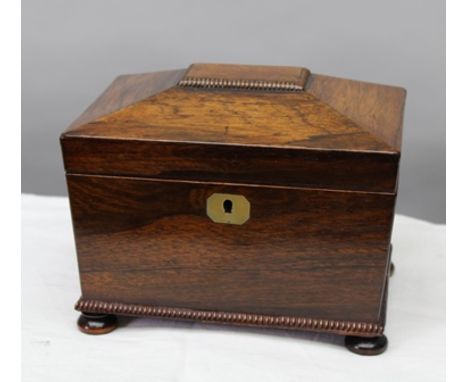 A 19TH CENTURY ROSEWOOD TEA CADDY, the hinged cover opening to reveal two inner lidded compartments, raised on bun feet 
