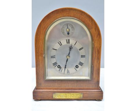 AN EARLY 20TH CENTURY OAK AND PLATE GLASS CASED MANTEL CLOCK, having eight day striking movement, arched silvered dial, the c