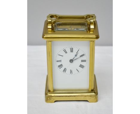 A 20TH CENTURY BRASS FRAMED CARRIAGE CLOCK fitted bevelled glass panels, the white enamel dial with Roman numerals, 11cm high