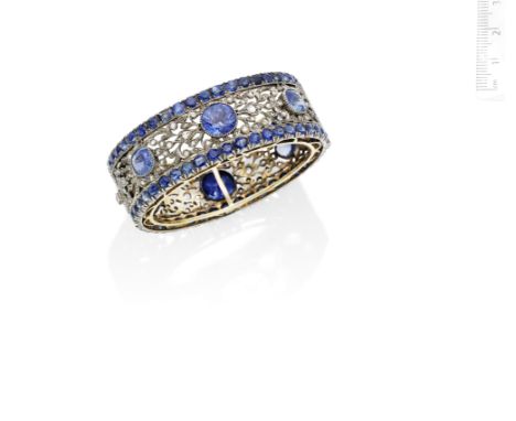 A mid 20th century sapphire and diamond bangleThe hinged bangle of openwork foliate design, set with six circular and oval-cu