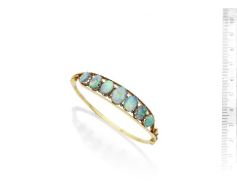 An opal bangle, circa 1900The openwork knife-edge bangle set with a graduated row of oval cabochon opals, inner diameter 6.0c