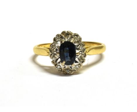 18CT GOLD SAPPHIRE CLUSTER RING The cluster measuring 1.1 x 0.9cm and set with a central oval blue sapphire on a white metal 