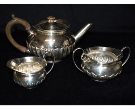 A SILVER THREE PIECE TEA SET The tea set in same design of ribbed belly's and wave rims, the tea pot with brown resin handle 