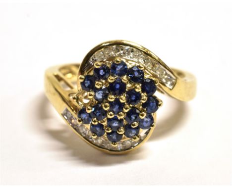 QVC 9CT GOLD, GEM SET WRAP OVER CLUSTER RING The cluster set with blue gemstones with a diamond overlay wrap, the yellow gold