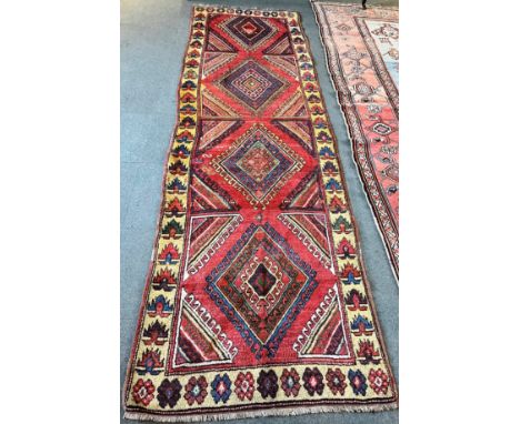 A RED GROUND RUNNER  with four loznge medallions, 115cm x 365cm