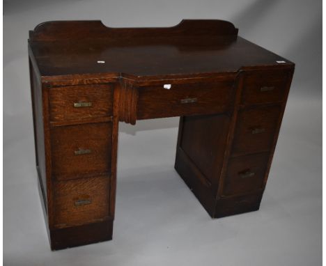 An early to mid 20th Century post Deco oak dressing table having ledge back (no mirror) , the breakfront centre drawer flanke