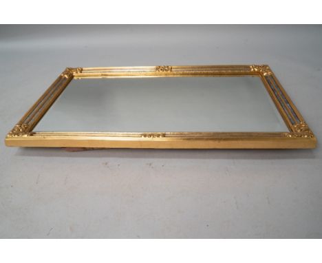 A modern reproduction gilt frame wall mirror in the classical style with foliate embellishments, and frame edged with burnish