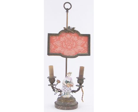 An early 19th century ormolu and marble twin branch lamp,surmounted by a German porcelain figure of a woman playing a hurdy-g