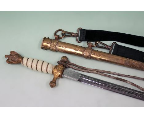 A German WWIII naval dagger with etched blade in brass scabbard. The hilt with eagle pommel, c/ knot and hanging straps.