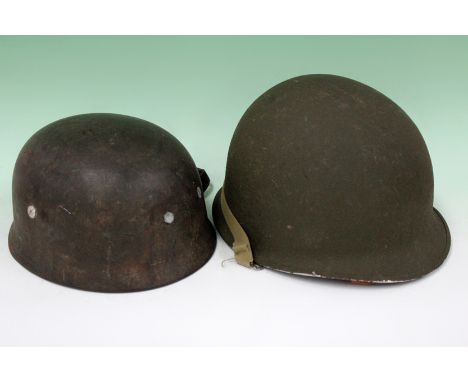 A WWII German paratroopers helmet with lining and straps together with an American helmet.