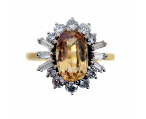 A topaz and diamond cluster ring, the oval shape golden topaz within a brilliant and baguette cut diamond surround, stamped 1