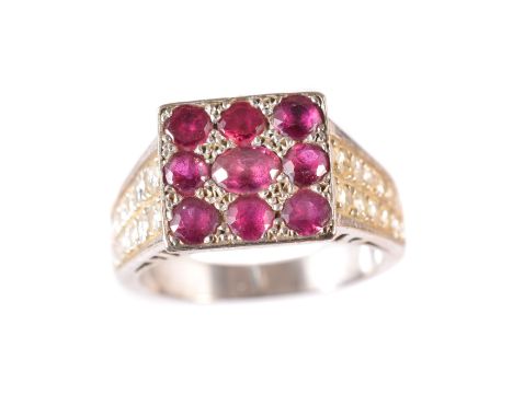 A ruby and diamond dress ring, the oval and circular shape ruby cluster within a square shape panel, with tapered vari-cut di