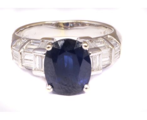 A sapphire and diamond dress ring, the oval shape sapphire with baguette cut diamond sides and similarly cut diamond tapered 