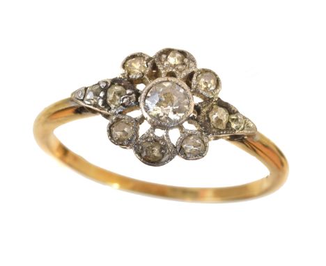 An early 20 th Century diamond cluster ring retailed by Wartski, of floral design the circular cut diamond collet within an o