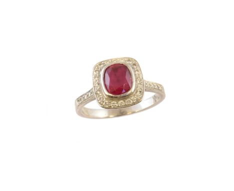 A platinum ruby and diamond cluster ring, the cushion shape ruby within a brilliant cut diamond halo surround and similarly c