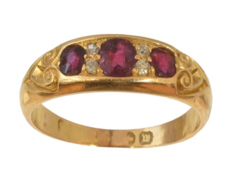 A late Victorian 18ct gold ruby and diamond dress ring, the cushion shape ruby line with old cut diamond duo spacers and scro