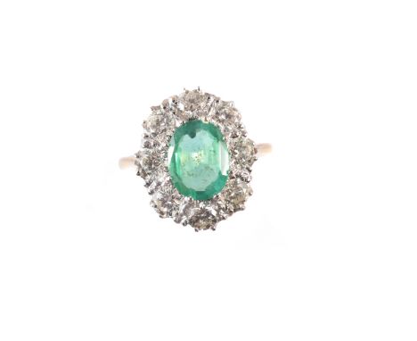 An emerald and diamond cluster ring, the oval shape emerald within a brilliant cut diamond surround, stamped 18ct, estimated 