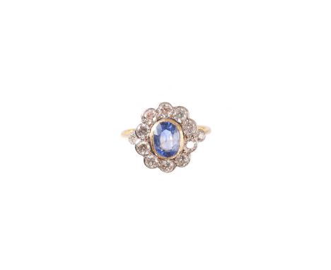 A sapphire and diamond cluster ring, the oval shape sapphire within a brilliant cut diamond scalloped surround and similarly 