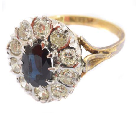 An 18ct gold sapphire and diamond cluster ring, the oval shape sapphire within a brilliant cut diamond surround, hallmarks fo