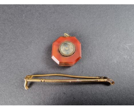 A red agate octagonal compass pendant, 22mm; together with a base metal riding crop bar brooch. (2) 