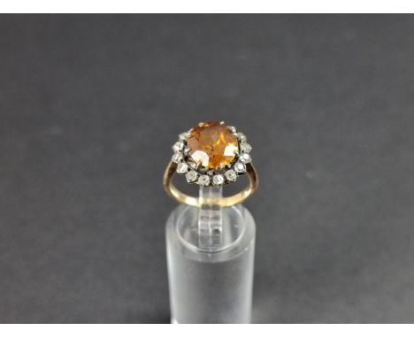 A yellow metal citrine and diamond cluster ring, set central faceted citrine surrounded by seventeen old cut diamonds, size M