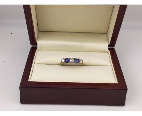 A yellow metal ring set with white and blue stones. Approx weight 2.4 grams, approx size R 1/2.