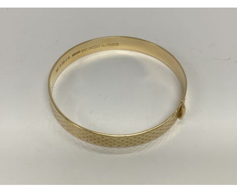A 9ct gold bangle with engraved chequered decoration. 15.3g. (A).