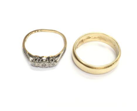 An 18ct gold band size K 1/2 and 18ct three stone ring size J. 5g total.