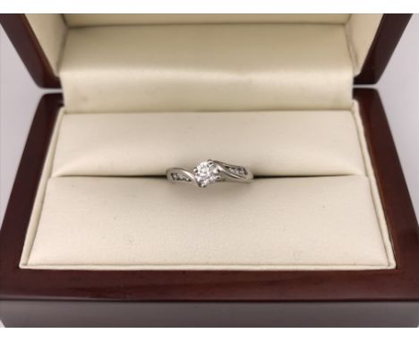 An 18ct white gold diamond set solitaire ring with diamonds set in the shoulders.