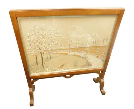 An early 20thC mahogany firescreen, with silk banner embroidered with a pheasant within an ornamental garden, on shaped legs,