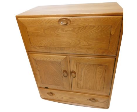 An Ercol light elm secretaire, the fall front, two doors and a drawer, each with shaped and turned wooden handles, on castors