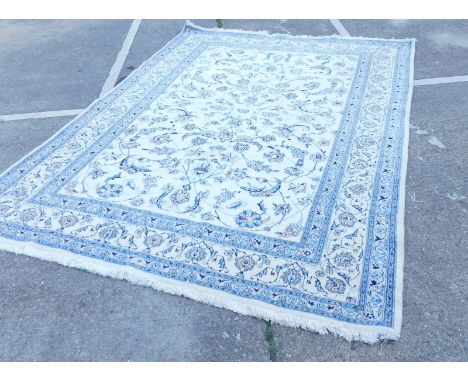 A Indian carpet with a design of flowers, scrolls, leaves, etc., on a cream ground within narrow blue borders, 247cm x 334cm.
